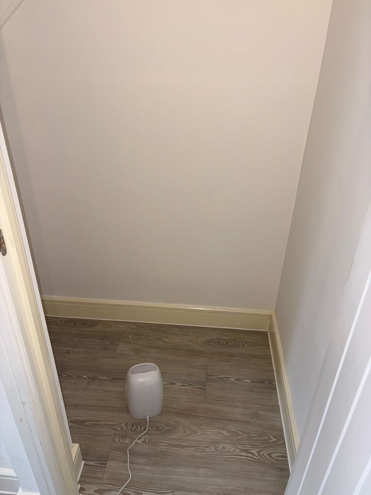 The same corner after remediation: clean wall and skirting, with a dehumidifier drying the room