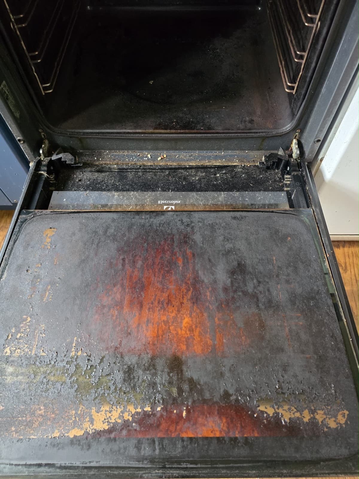 An oven interior heavily coated in burnt-on grease and carbon