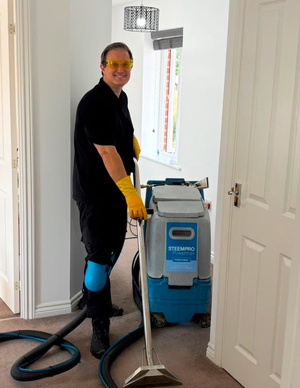 A team member operating a commercial carpet extraction machine in a hallway