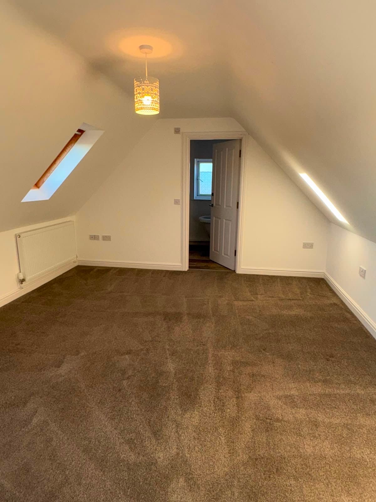 A freshly cleaned carpet in an empty loft room, with visible pile grooming lines
