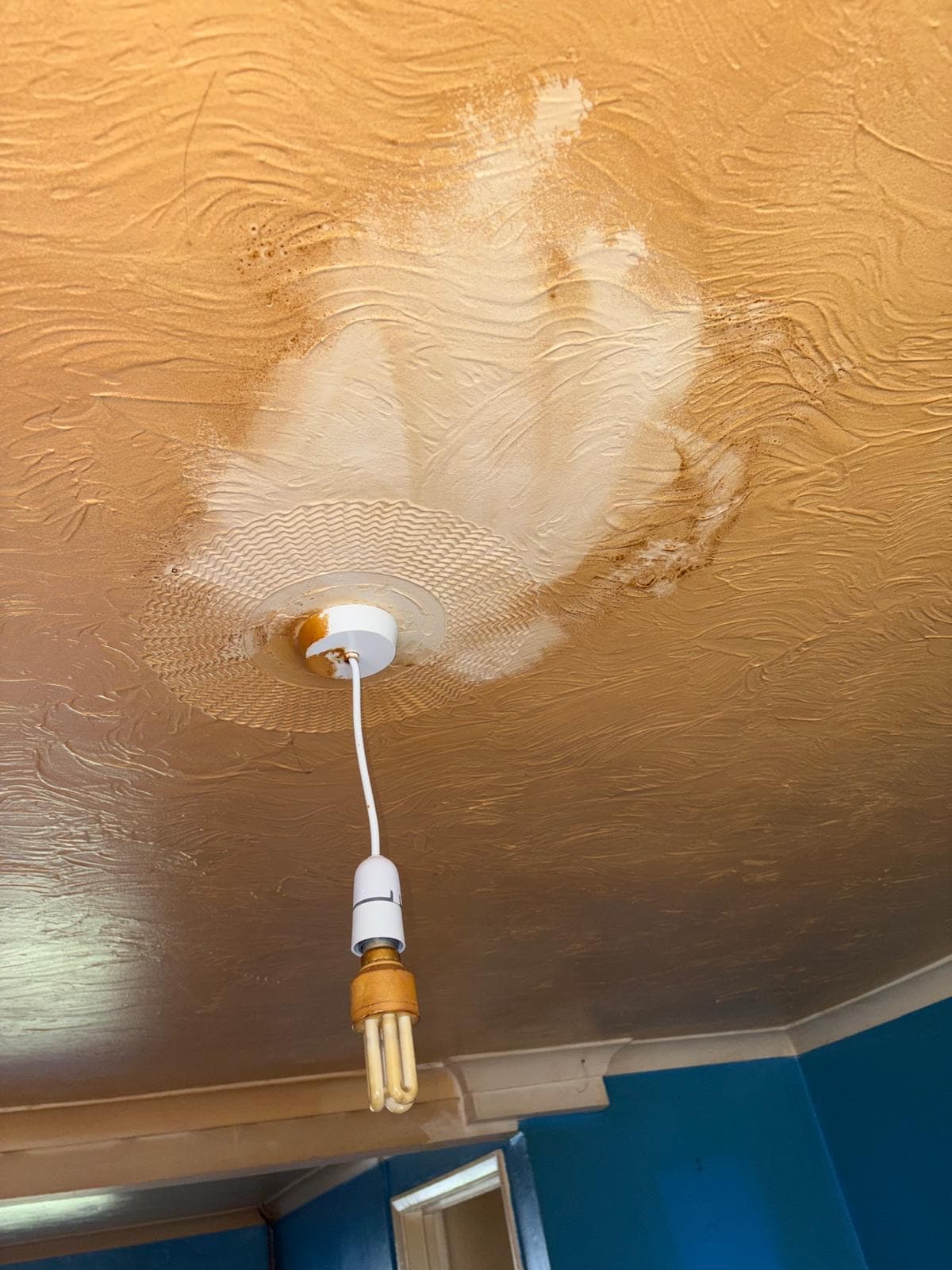 A nicotine-stained ceiling with a cleaned patch revealing the original white paint